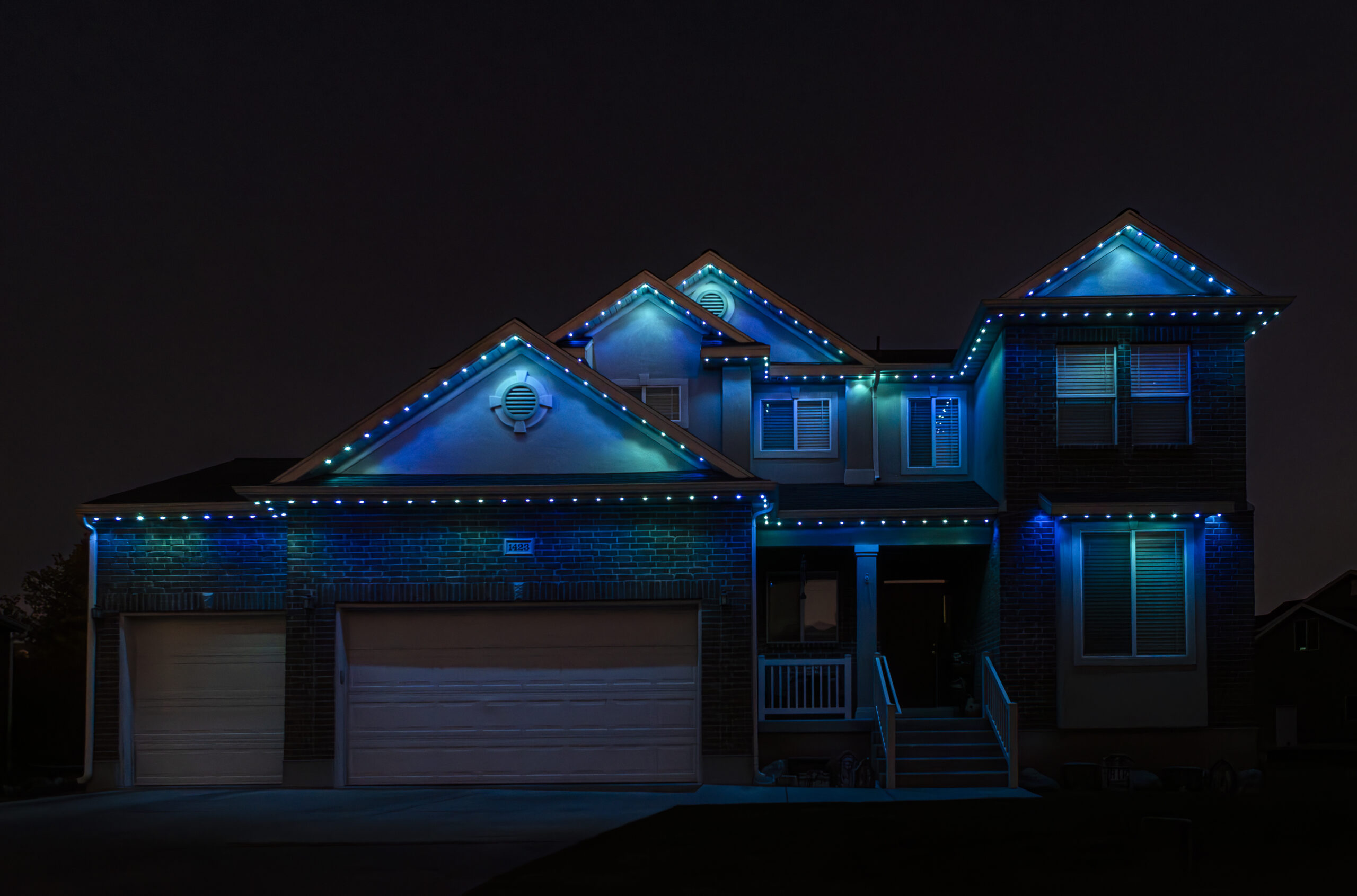Permanent lighting, caught here in teal at dusk. The same track sits on the gables all year — you just change the color when the season does.